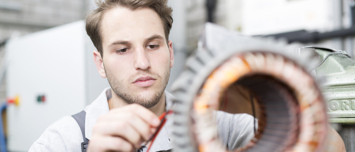 Handwerker können sich hier für den Meisterinnovationspreis bewerben. Ein junger Mann arbeitet in einer Werkstatt konzentriert an einem Objekt, das im Vordergrund nur unscharf zu erkennen ist.