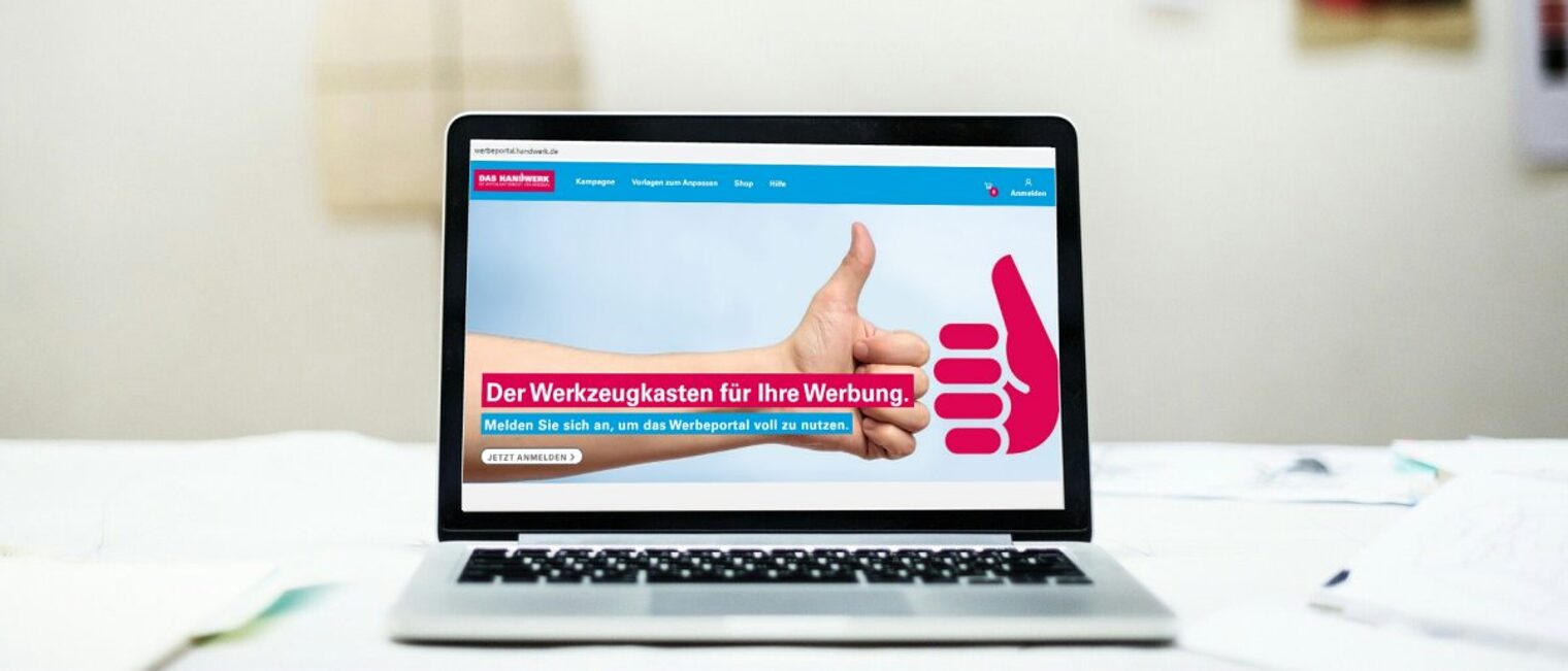 Im neuen Werbeportal finden Handwerksbetriebe praktische Werbevorlagen Ein geöffneter Laptop auf einem weißen Tisch in einem hellen Raum. Bildschirm zeigt die Startseite einer Webseite zu Werbung.