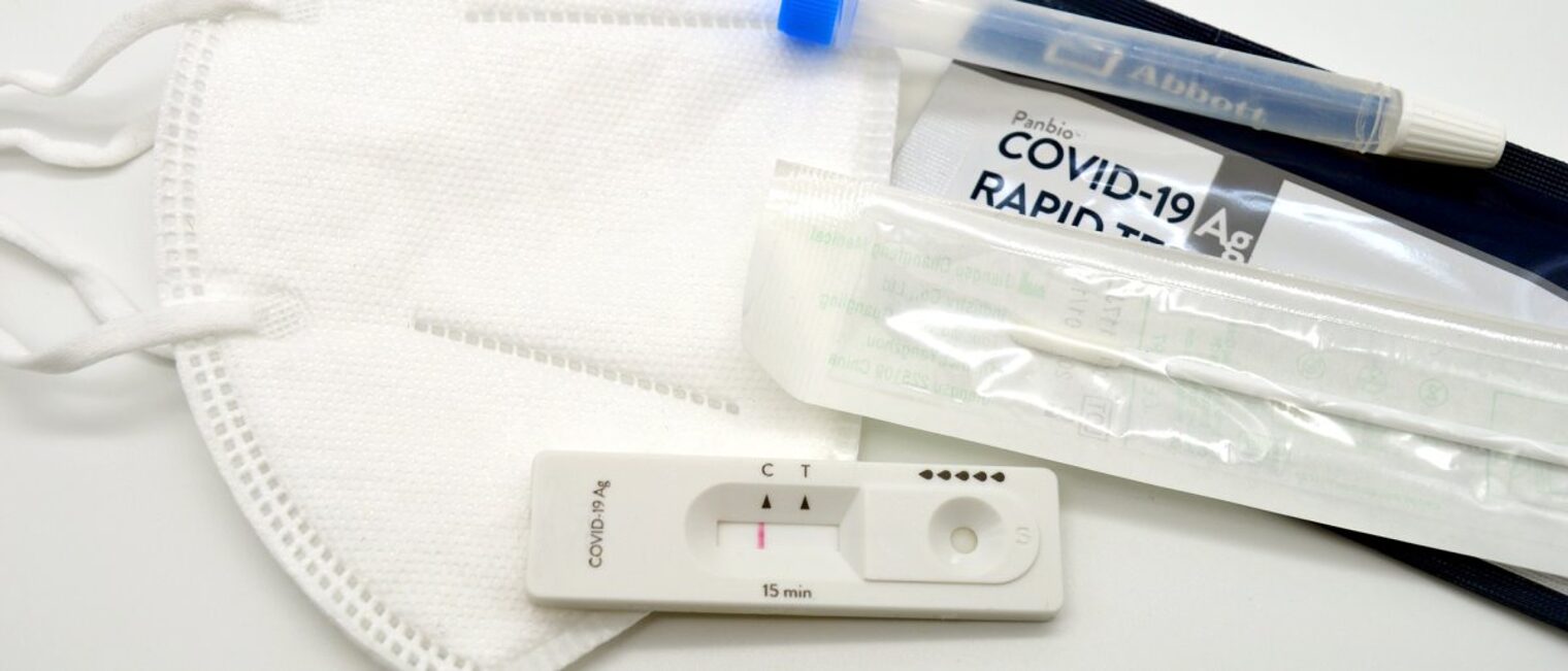 In der Basisstufe gelten die 3G-Regeln auch mit Antigen-Schnelltest. Auf weißem Hintergrund liegen eine FFP2-Gesichtsmaske und die einzelnen Bestandteile eines Covid-19-Testkits.
