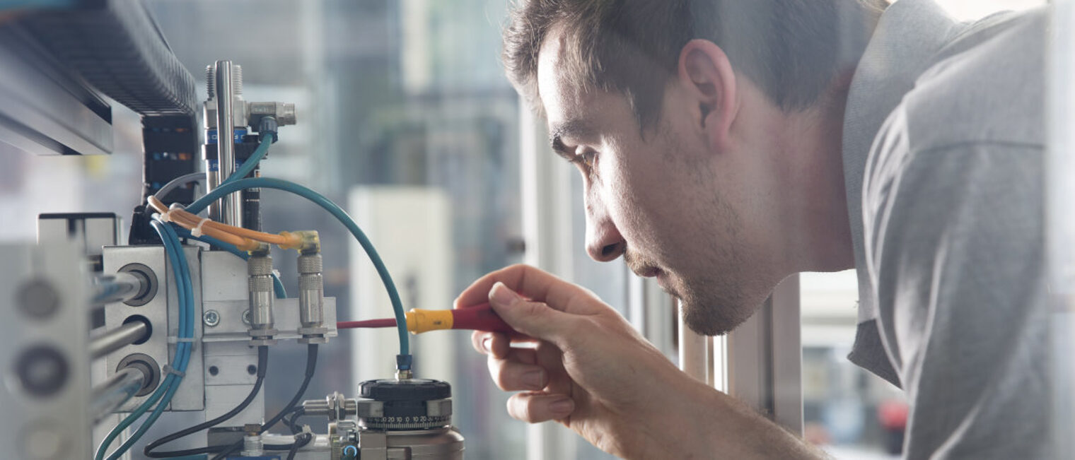 Handwerker können sich für den Meisterinnovationspreis bewerben. Zu sehen sind Kopf und Oberkörper eine jungen Mannes der mit einem Schraubendreher in der Hand an einer Maschine arbeitet.