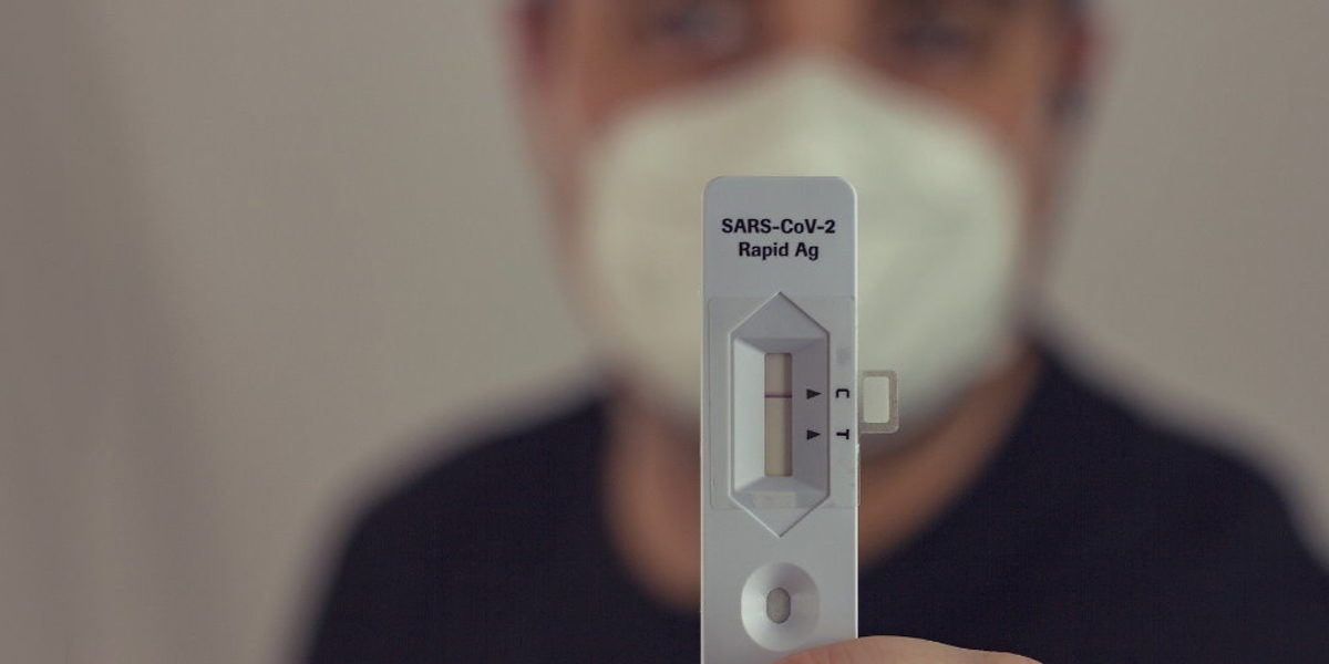 Für einen Friseurbesuch reicht jetzt auch ein negativer Selbsttest. Ein Mann mit einer FFP2-Maske hält einen Selbsttest auf das Coronavirus in die Kamera, um das negative Ergebnis zu zeigen.