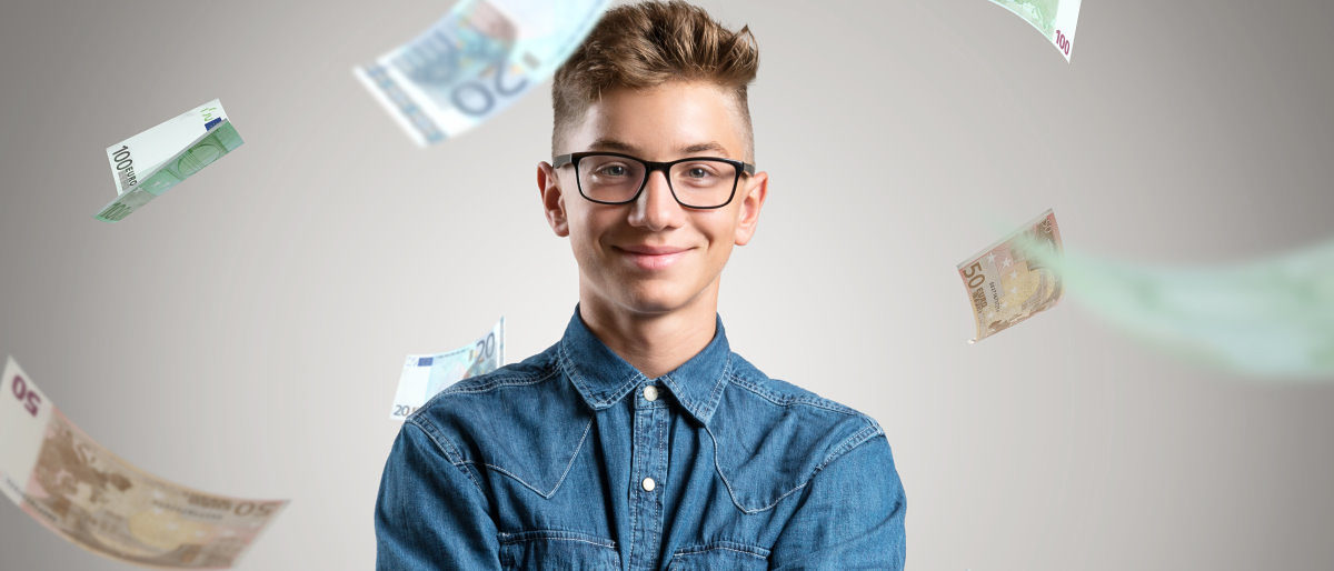 Porträt eines jungen Mannes mit Brille und in Jeanshemd vor einem grauen Hintergrund. Um ihn herum regnet es Euroscheine.