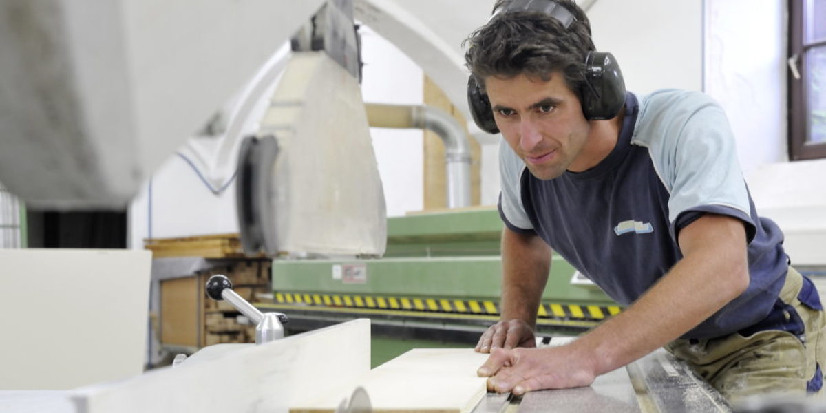 Top Gründer im Handwerk 2021 - Wettbewerb für Gründer und Nachfolger Schreiner bei der Arbeit in der Werkstatt, sägt Holzbrett an großer Maschine