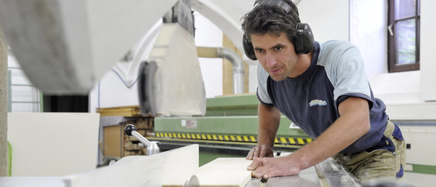 Top Gründer im Handwerk 2021 - Wettbewerb für Gründer und Nachfolger Schreiner bei der Arbeit in der Werkstatt, sägt Holzbrett an großer Maschine