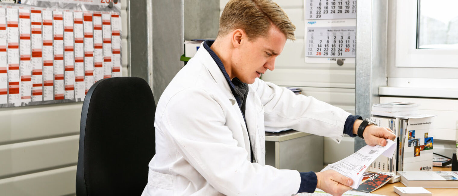 Handwerker sitzt am Schreibtisch und schaut verärgert auf einen geöffneten Brief