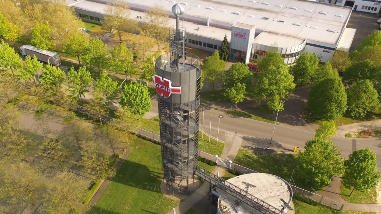 Drohnenaufnahme des Würth-Solarturms. Im Hintergrund steht ein Firmengebäude.