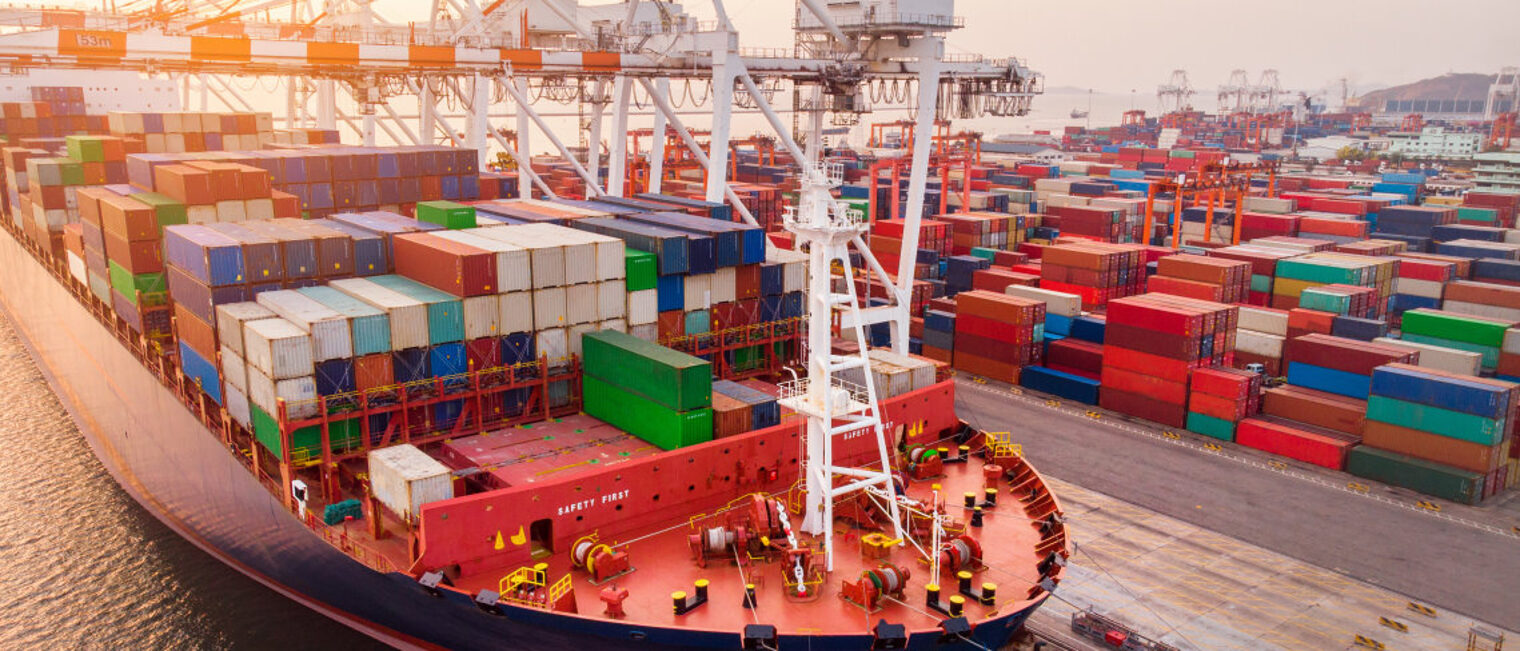 Durch die Corona-Pandemie und den Ukraine-Krieg kommt es häufig zu Lieferengpässen. Ein im Hafen liegendes großes Containerschiff wird mit einem Frachtkran beladen.
