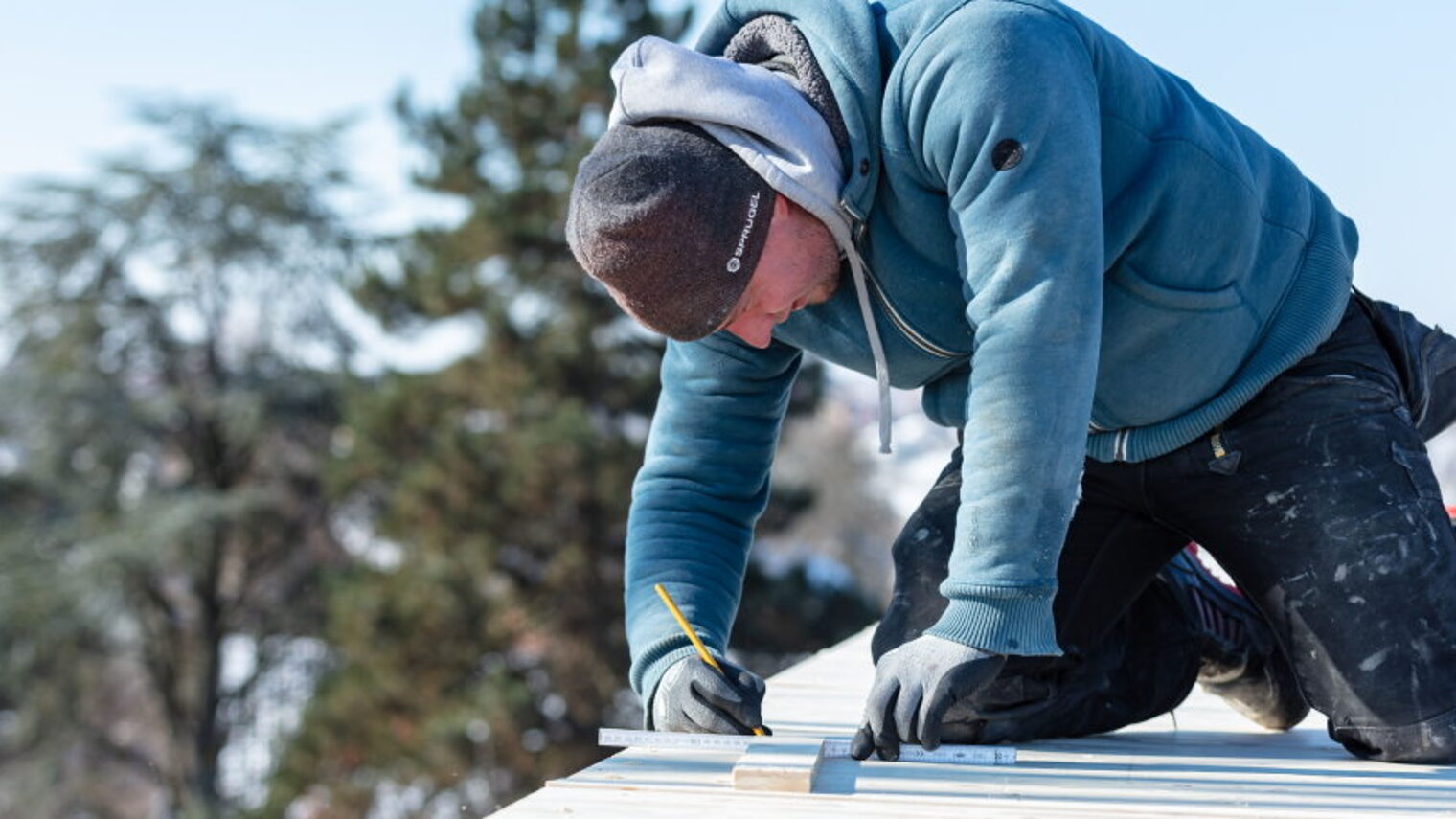 Handwerker kniet auf Dach und vermisst.