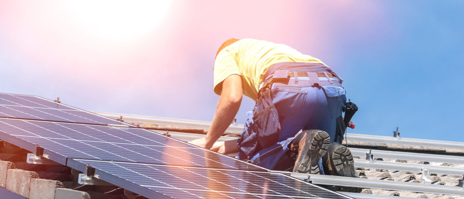 Handwerker installiert Photovoltaik-Panel auf einem Dach