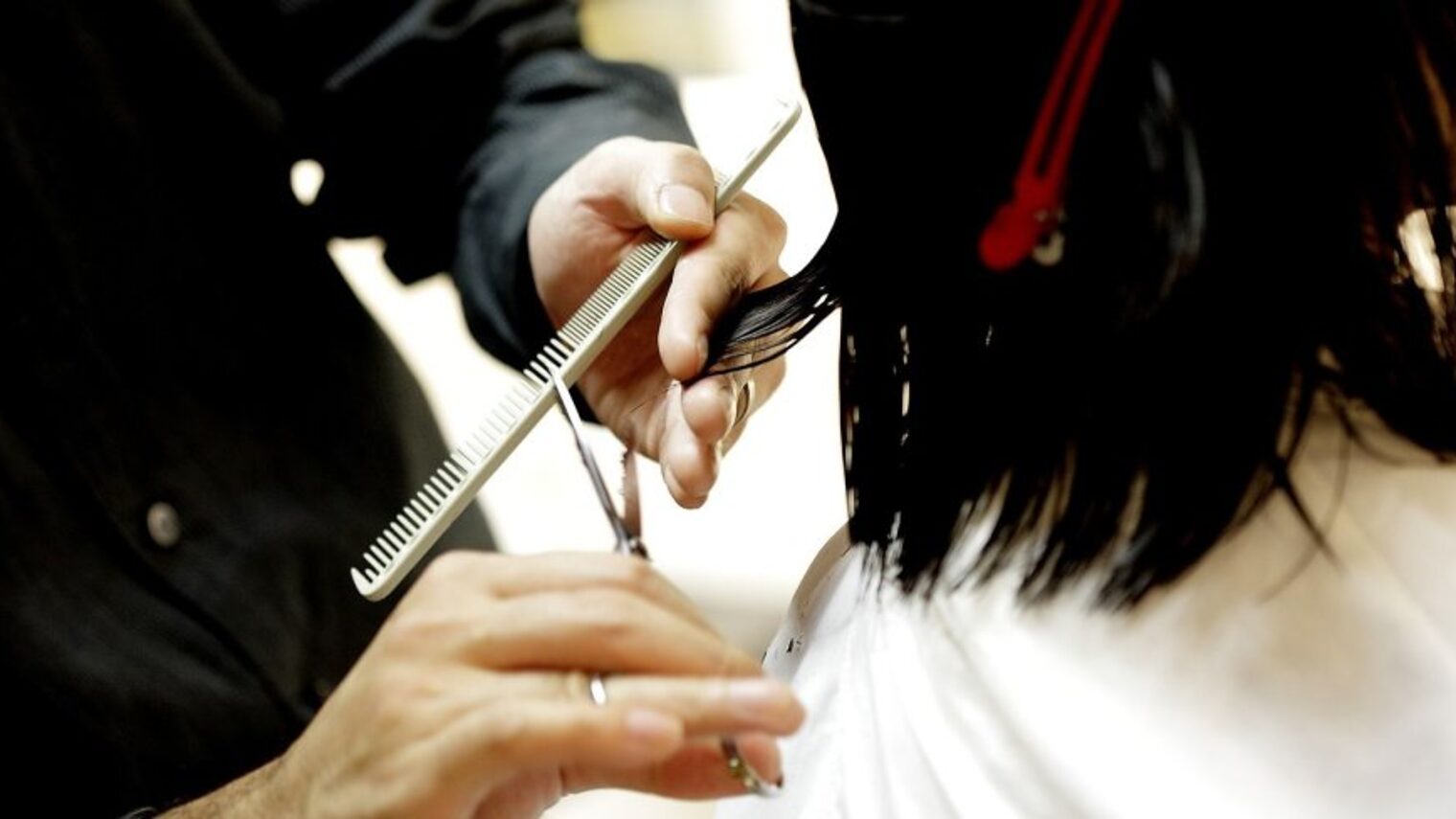 Friseur schneidet Haare bei einer Frau