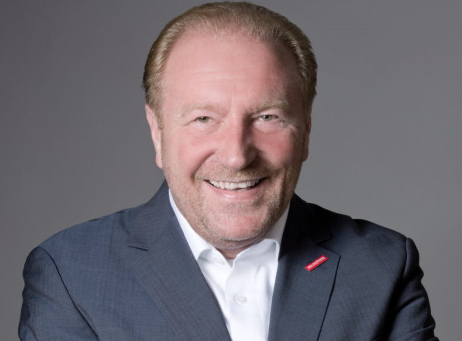 Ein Mann in einem dunklen Anzug lächelt in die Kamera.