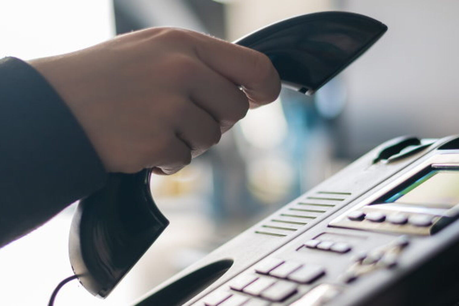 Eine Hand hält einen Telefonhörer.