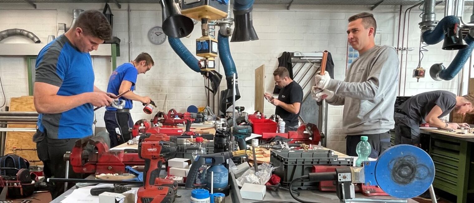Die Handwerkskammer bietet eine Vielzahl an Weiterbildungen an. Fünf junge Männer arbeiten an einer Werkbank.