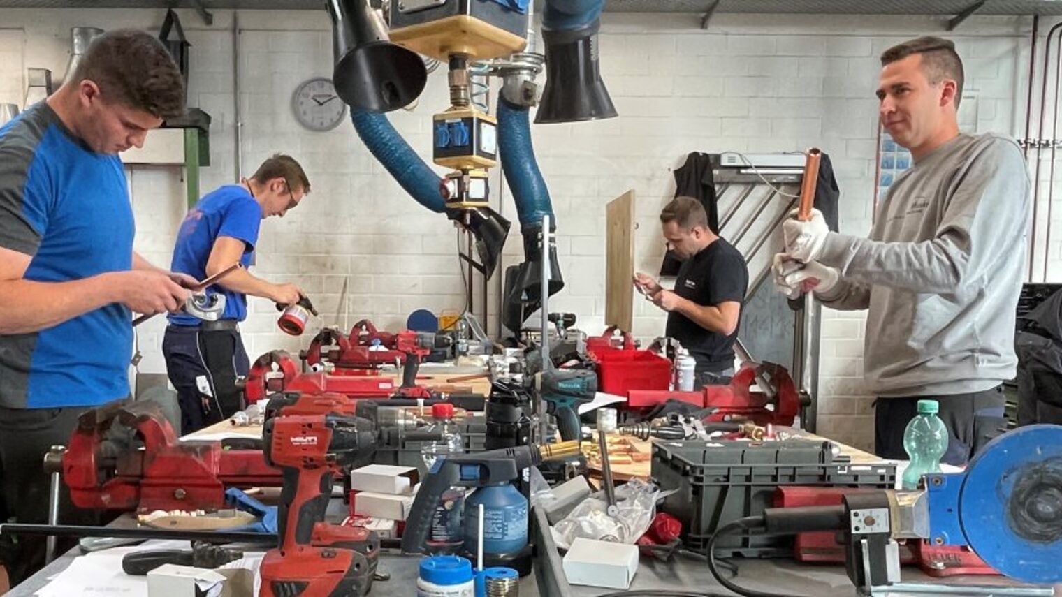 Fünf junge Männer arbeiten an einer Werkbank.