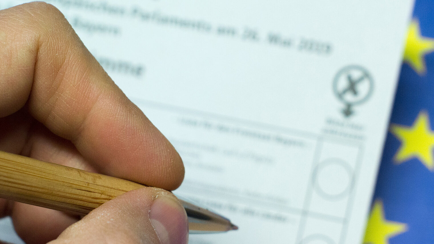 Ein Mann macht ein Kreuz auf einem Stimmzettel für die Europawahl. 