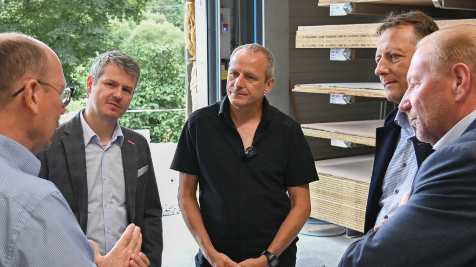 Fünf Männer stehen in einer Halle im Halbkreis und unterhalten sich. 