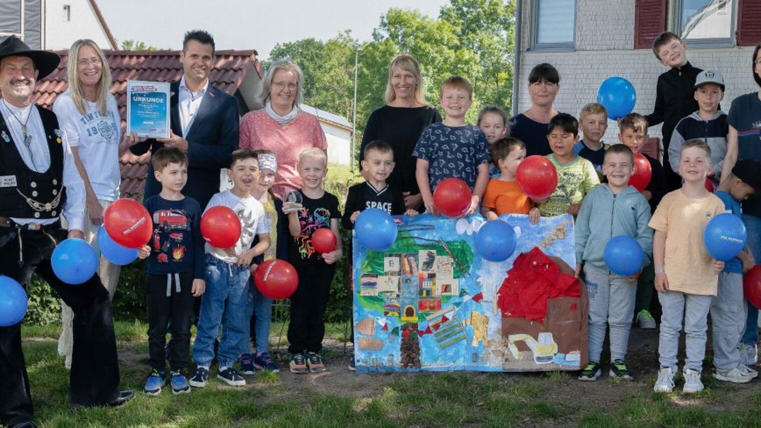 Eine Gruppe mit mehreren Erwachsenen und Kindern steht in einem Garten. 