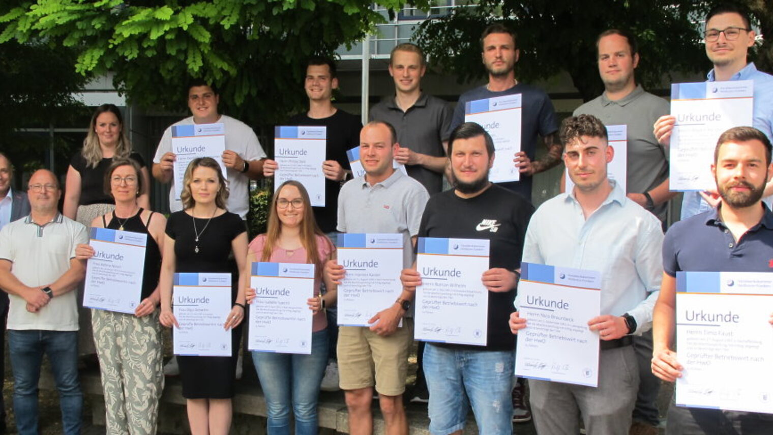 Gruppenfoto mit 17 Personen, 13 halten eine Urkunde in der Hand.