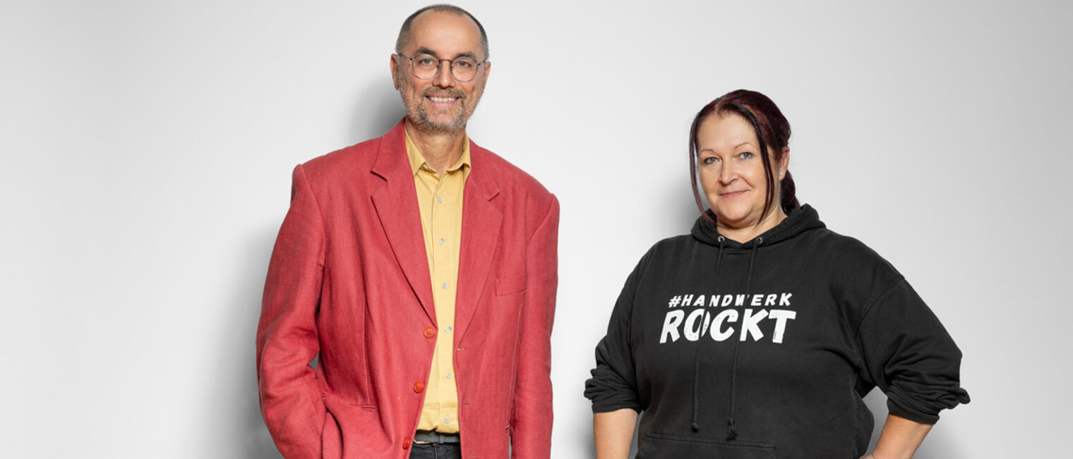 Ein Mann mit rotem Jacket und eine Frau mit einem schwarzen Pullover lächeln in die Kamera.