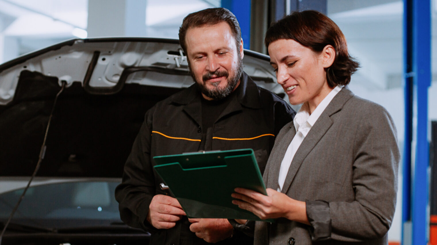 Ein Mann und eine Frau, die eine Mappe in der Hand hält, stehen in einer Werkstatt.