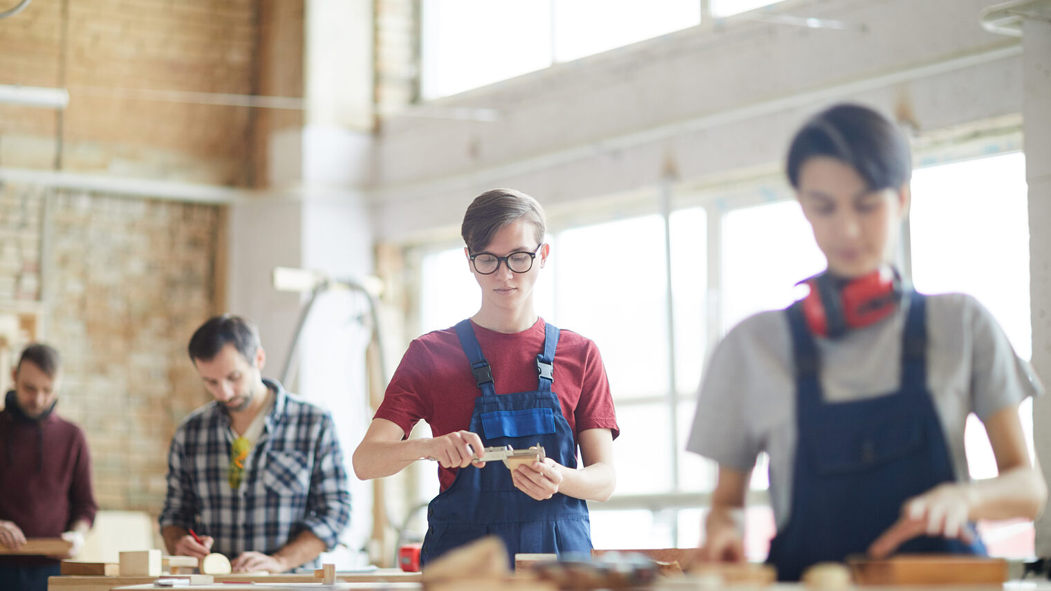 Portrait von modernen Schreinern, die in einer Werkstatt mit Holz arbeiten.