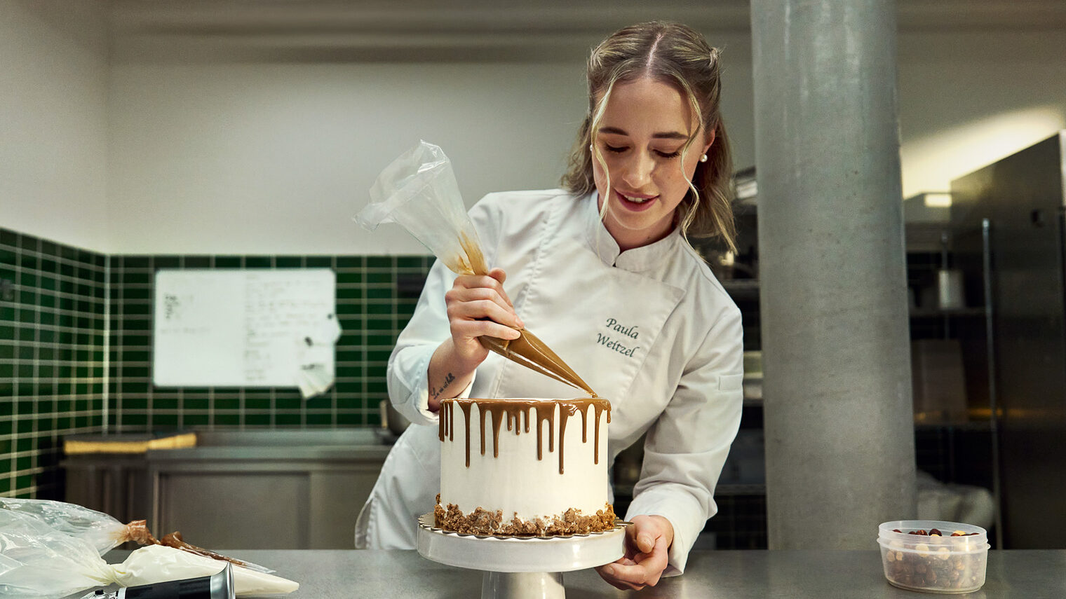 Anzeige der Imagekampagne des Handwerks: Eine Konditorin dekoriert eine Torte mit einer Spritztülle.