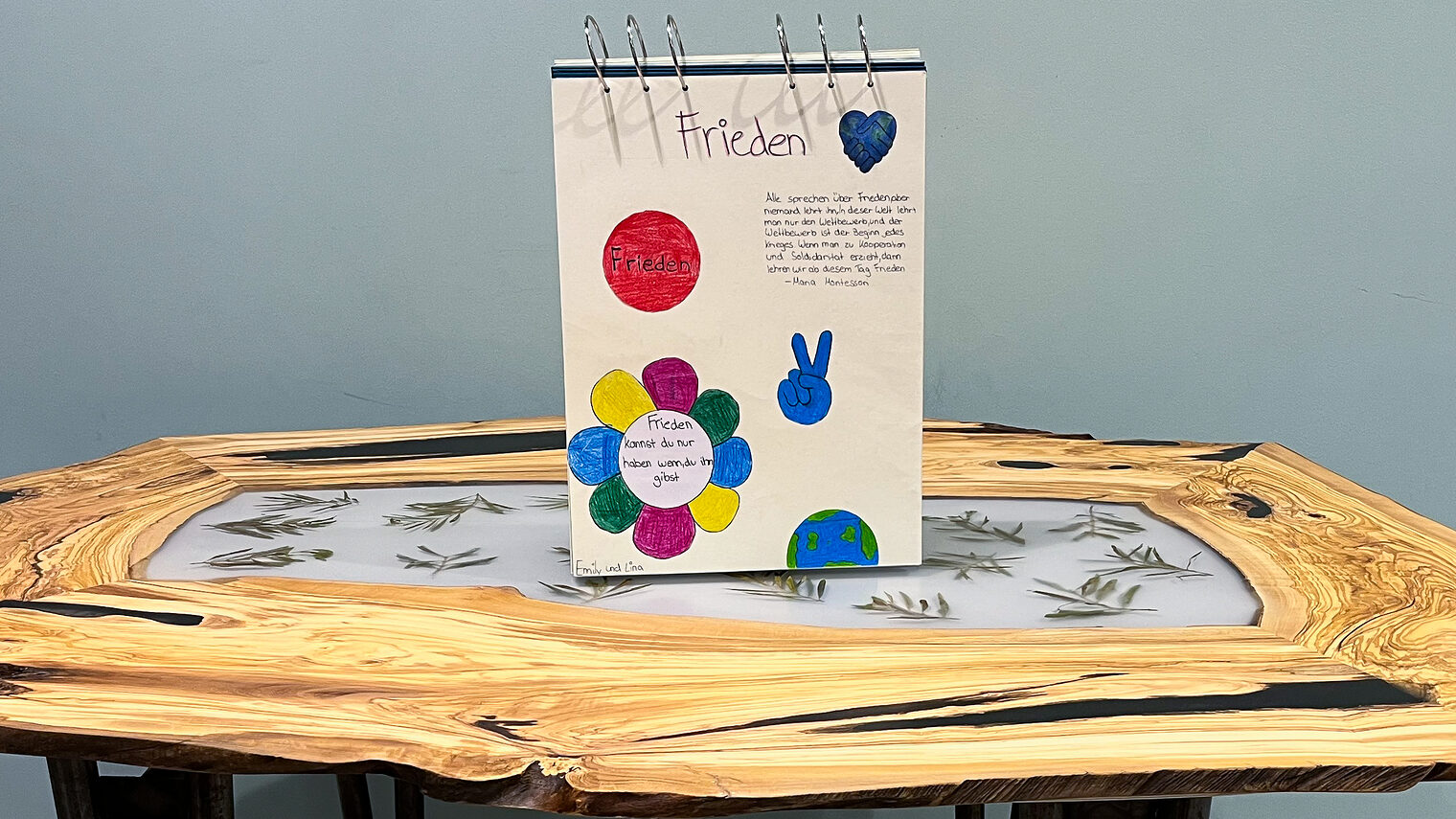 Auf einem Tisch aus Olivenholz steht ein Friedensbuch. Beides wurde von einer Schulklasse gestaltet.
