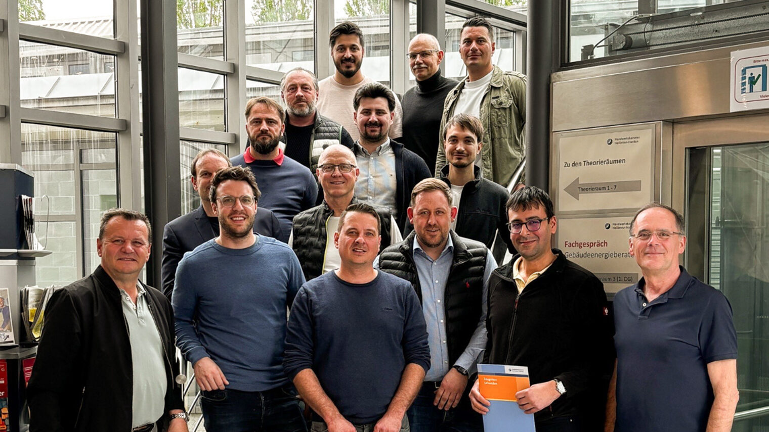 Eine Gruppe von Männern steht auf einer Treppe. Einzelne halten eine Urkunde in der Hand. 
