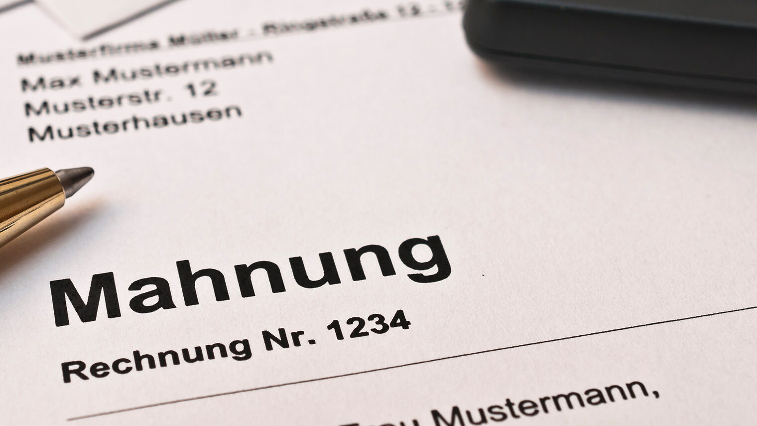 Ein Stift und ein Taschenrechner liegen auf einer Mahnung.