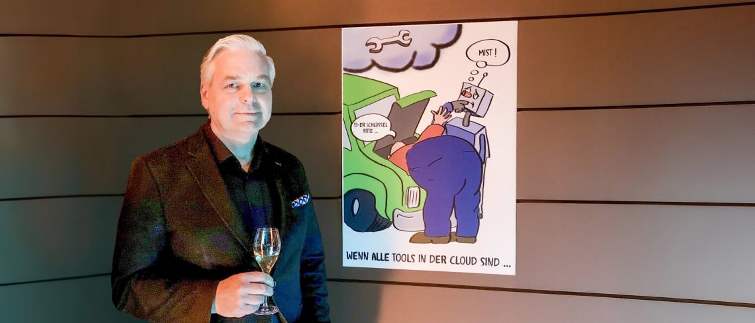 Marco Prosen hat an einem Karikaturenwettbewerb teilgenommen. Ein Mann steht mit einem Sektglas vor einer Karikatur.