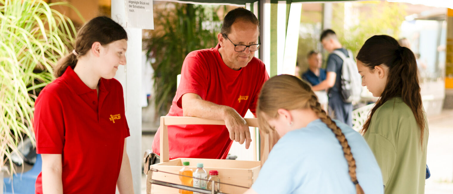 Stand der Schreiner-Innung Hohenlohe am Handwerkertag in Künzelsau. Ein Mann steht mit drei jungen Frauen an einem Tisch, auf dem sich verschiedene Sägen befinden.