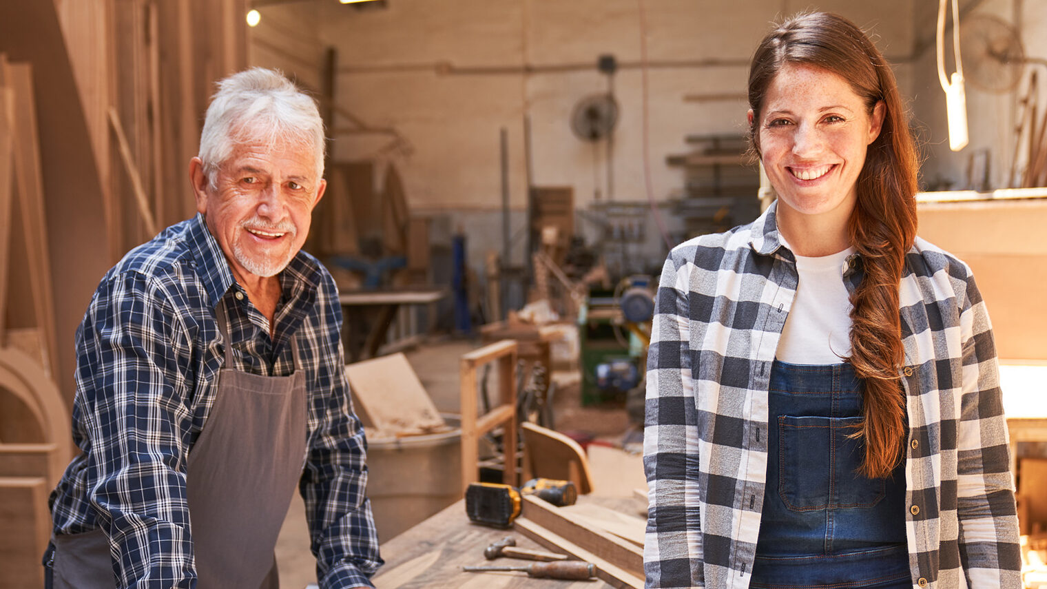 Handwerker-Senior mit junger Handwerkerin in Schreib´ner-Werkstatt