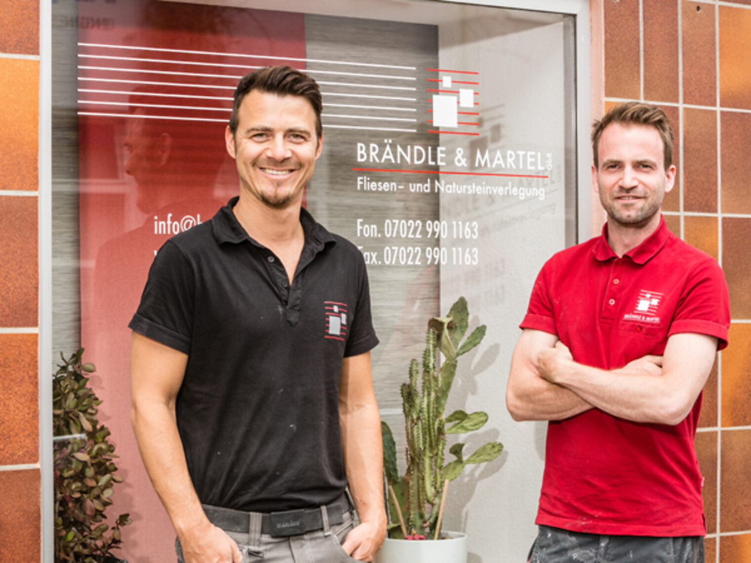 Zwei junge Handwerker stehen stolz vor ihrem Geschäft