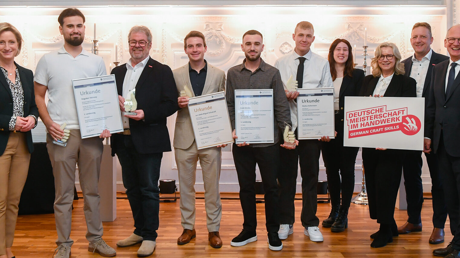 Im Rahmen einer Auszeichnung stehen mehrere Personen für ein Gruppenfoto nebeneinander und lächeln in die Kamera.