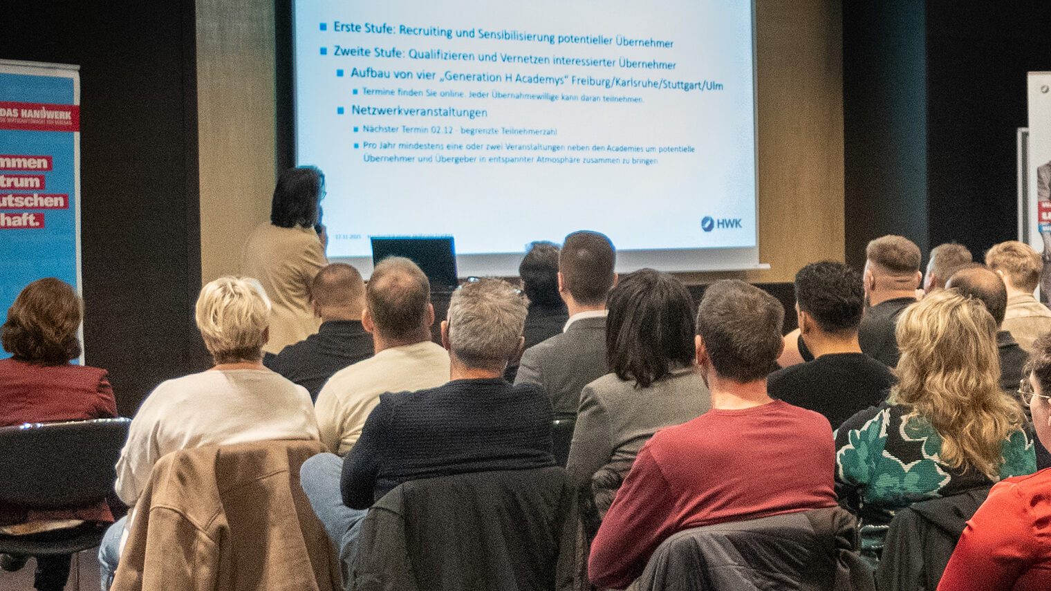 Eine Referentin spricht vor größerem Veranstaltungspublikum