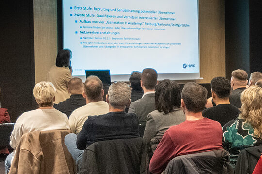 Eine Referentin spricht vor größerem Veranstaltungspublikum