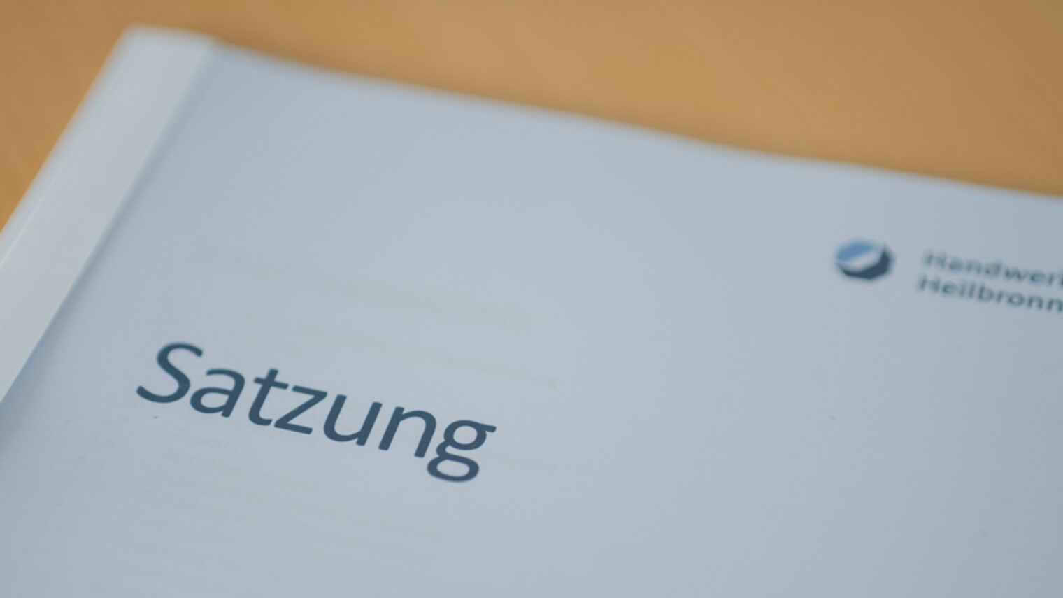 Auf einem Holztisch liegt ein Dokument mit dem Titel Satzung. 