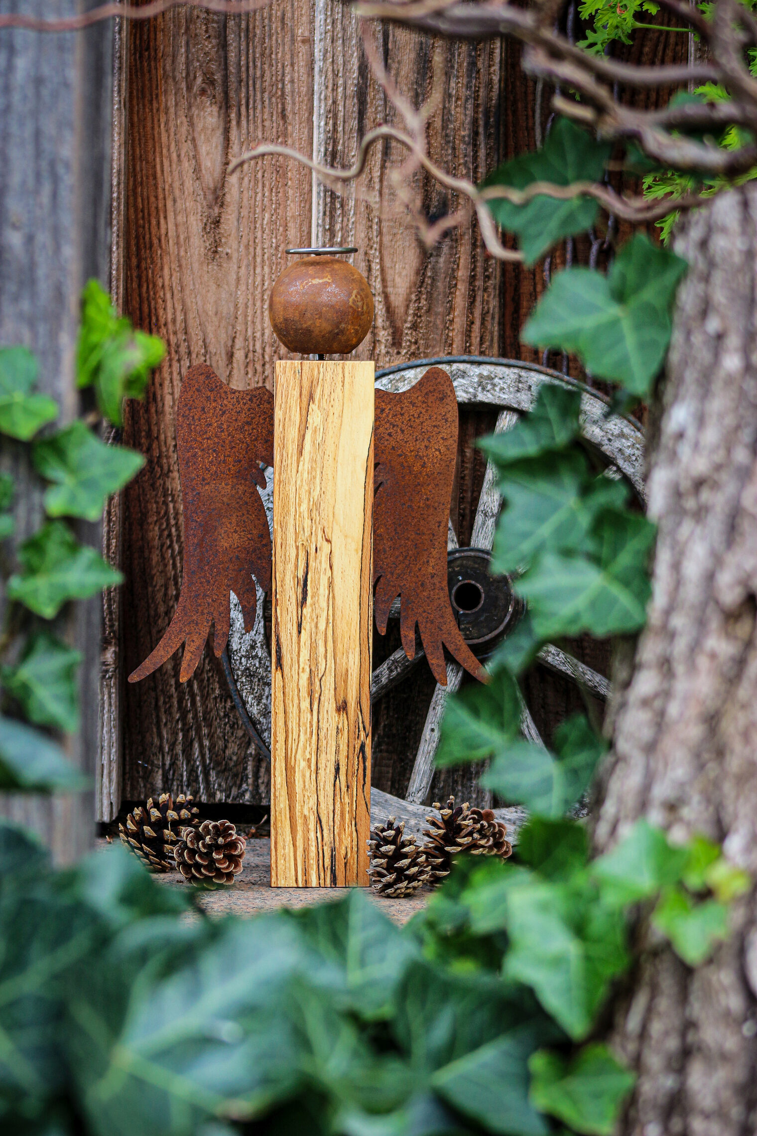 Engel mit einem Körper aus einem Holzbalken, Kopf und Flügel sind aus Edelrost.