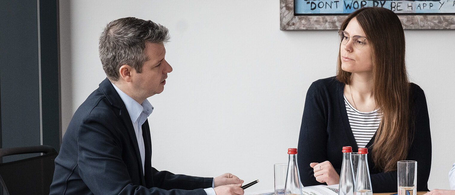 Ein Mann führt mit einer frau ein Beratunggespräch an einem Besprechungstisch