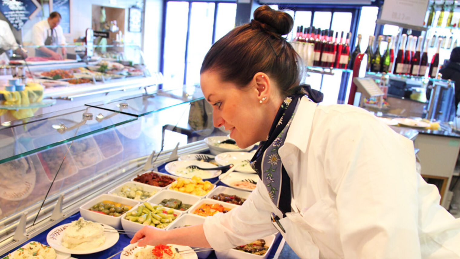 Eine Lebensmittelfachverkäuferin greift einen nach einem Teller.