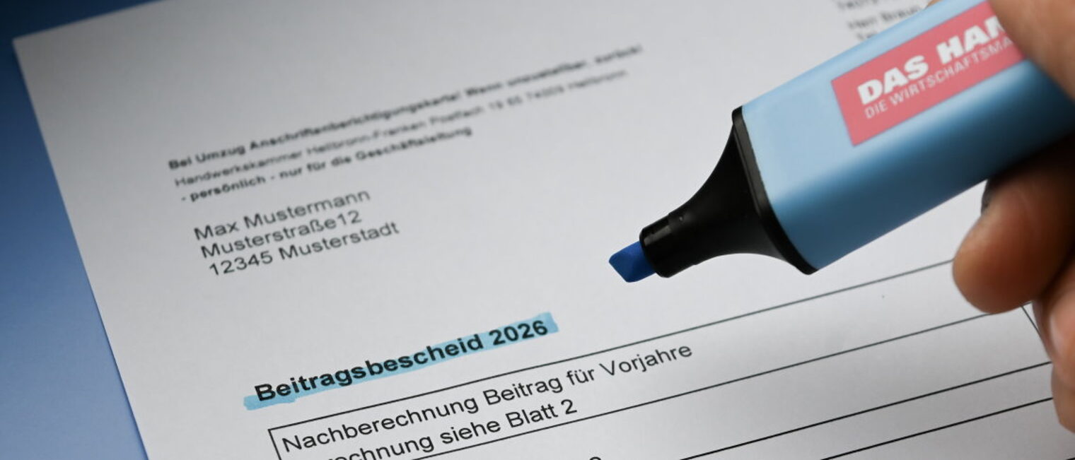 Ein Dokument mit dem Titel Beitragsbescheid 2026 liegt auf einem Tisch. 