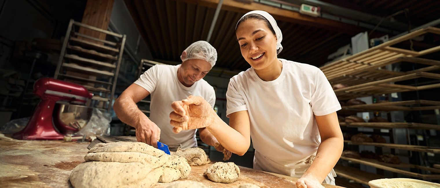 Eine Bäckermeisterin arbeitet in der Backstube und formt Brotteig.