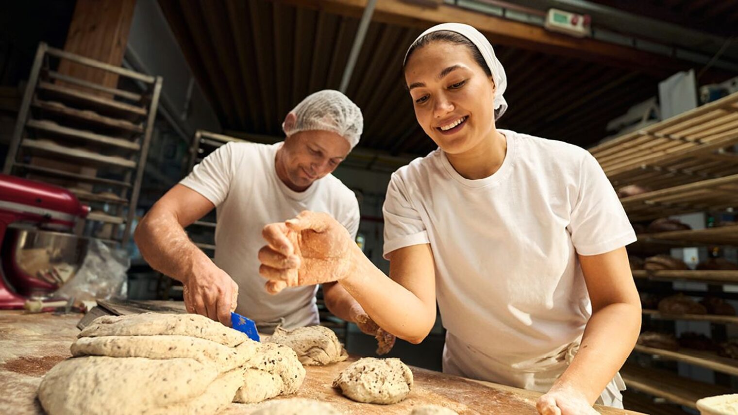 Eine Bäckermeisterin arbeitet in der Backstube und formt Brotteig.