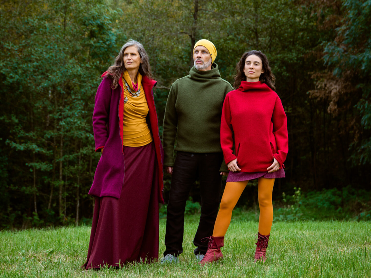Drei Personen stehen auf einer Wiese und tragen Mode aus bunten Naturfasern