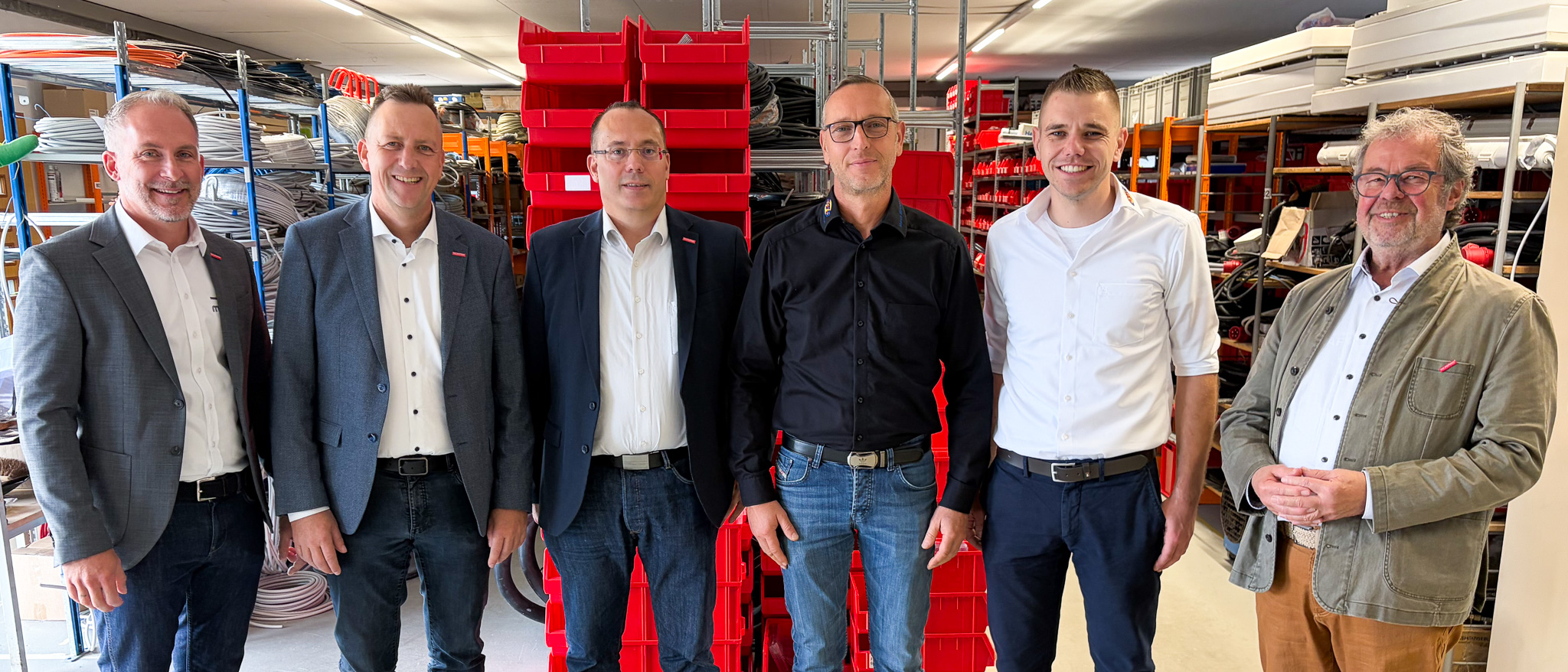 Für ein Gruppenfoto posiert eine Delegation von Handwerksvertretern im Lager eines Elektrobetriebs.