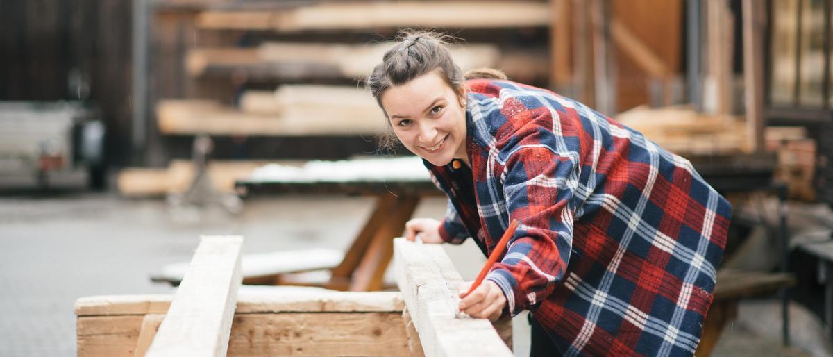 Eine junge Zimmerin arbeitet in der Holzwerkstatt.